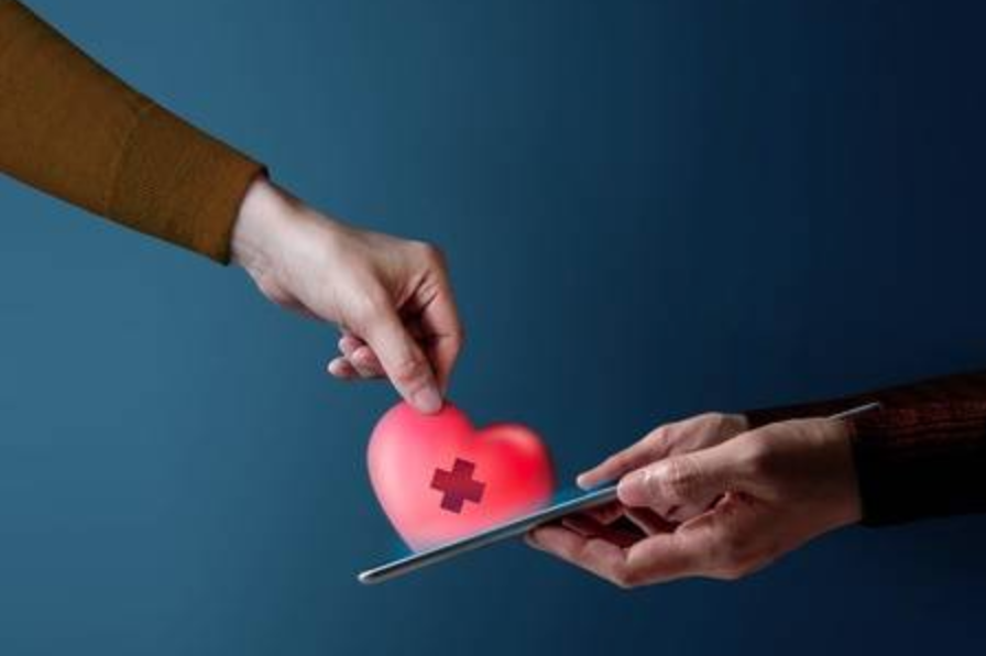 Hand inserting a heart graphic with a medical cross into a digital tablet